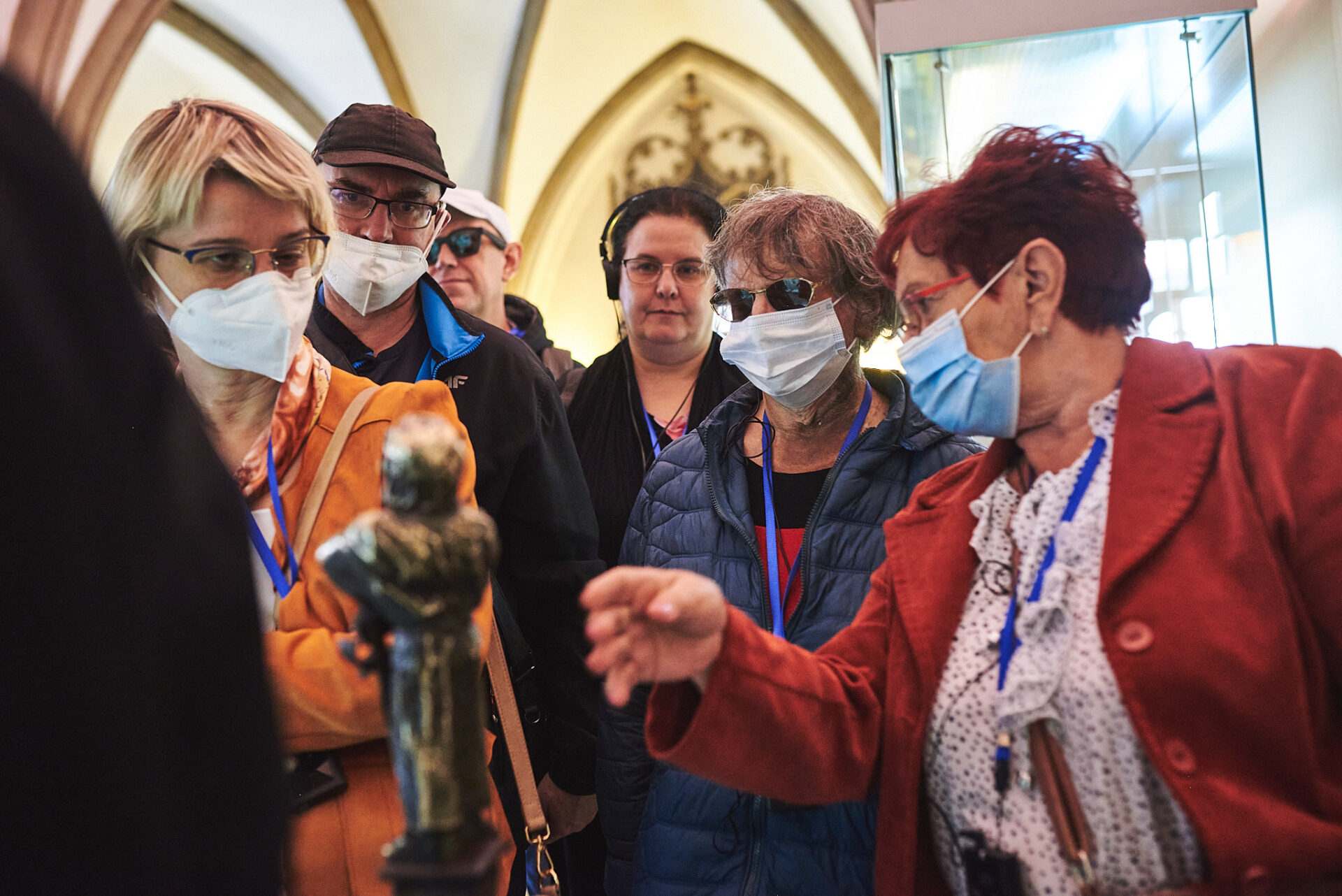 grupa uczestników oprowadzania po wrocławskim ratuszu z audiodeskrypcją obrajlowuje mały posążek wrocławskiego kata.