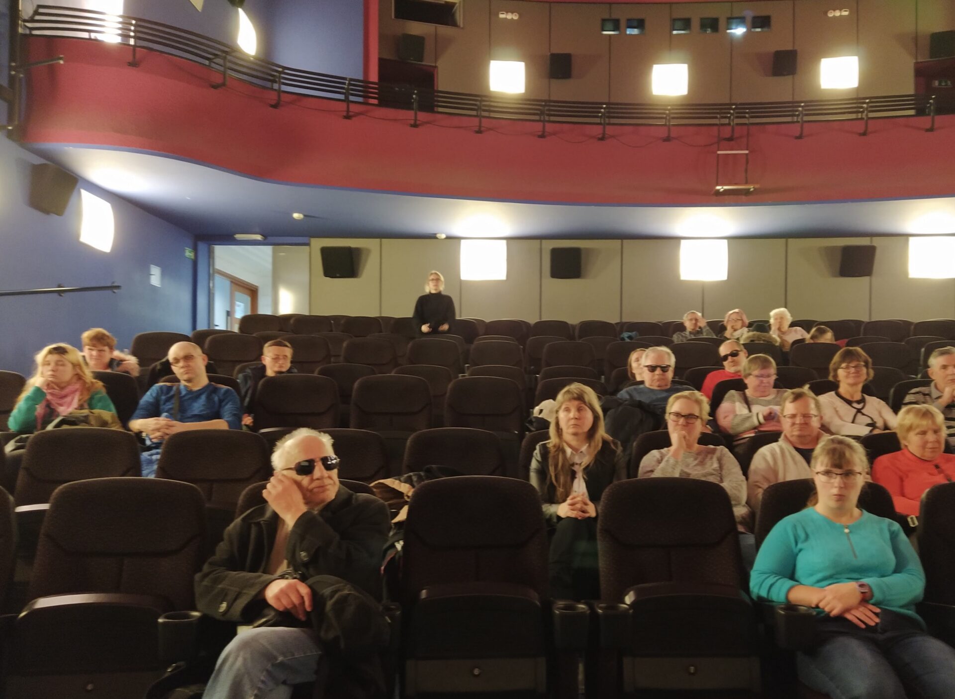widzowie w kinie podczass seansu filmu z audiodeskrypcją
