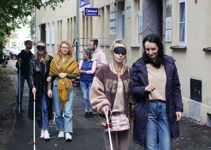 Kolorowa fotografia. Grupa dziewczyn ćwiczy chodzenie z białą laską.