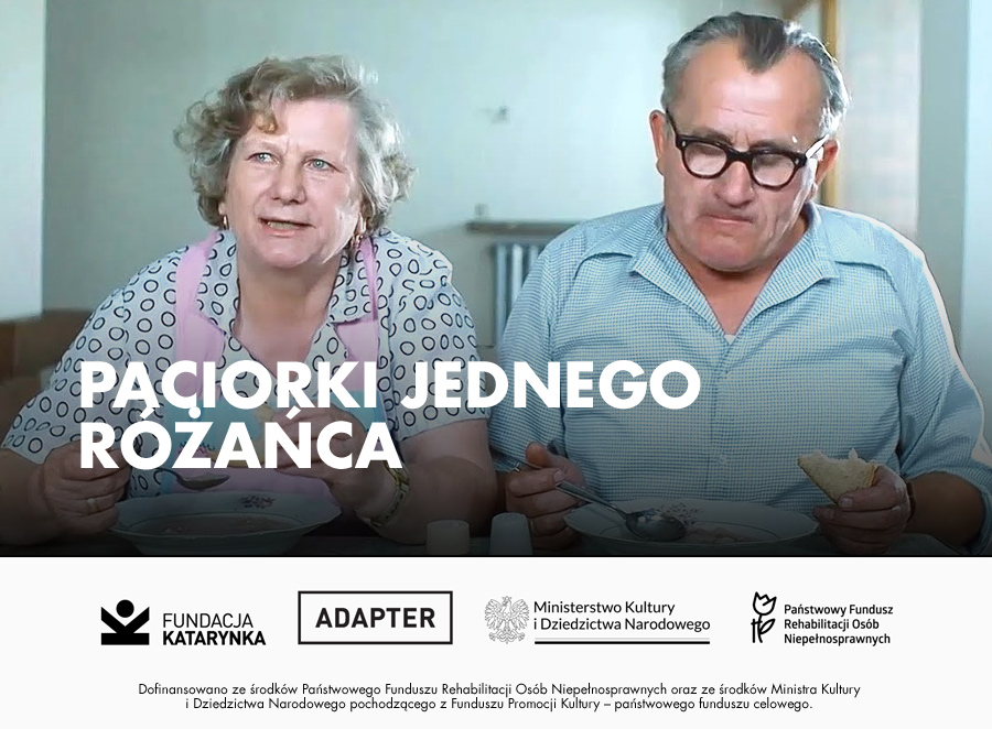 Kolorowy kadr z filmu Paciorki jednego różańca. Starsza kobieta z jasnymi, kręconymi włosami, ubrana w bluzkę w groszki i różowy fartuch, siedzi przy stole, trzymając widelec i jedzenie na talerzu. Obok niej mężczyzna w okularach i jasnoniebieskiej koszuli z krótkim rękawem spożywa posiłek, trzymając kromkę chleba w dłoni. Oboje znajdują się w skromnym wnętrzu, przypominającym typowe mieszkanie z czasów PRL-u. Poniżej na białym pasku logotypy: Fundacja Katarynka, Adapter, Ministerstwo Kultury i Dziedzictwa Narodowego, Państwowy Fundusz Rehabilitacji Osób Niepełnosprawnych. Poniżej napis: Dofinansowano ze środków Państwowego Funduszu Rehabilitacji Osób Niepełnosprawnych oraz ze środków Ministra Kultury i Dziedzictwa Narodowego pochodzącego z Funduszu Promocji Kultury – państwowego funduszu celowego.