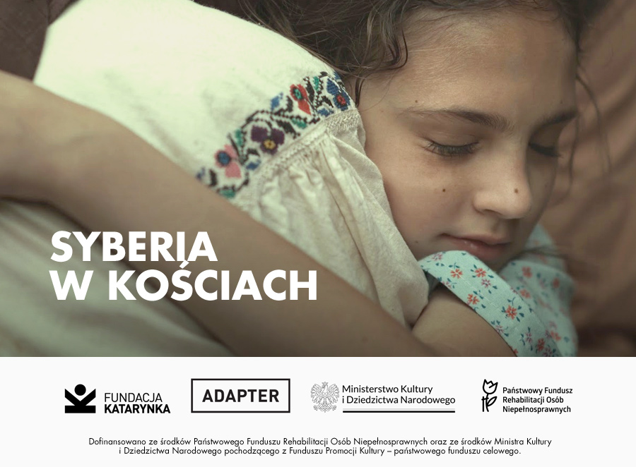 Kolorowy kadr z filmu Syberia w kościach. Zbliżenie na młodą dziewczynkę o ciemnych włosach, tulącą się do osoby ubraną w białą, haftowaną koszulę ludową. Poniżej biały pasek z logotypami: Fundacja Katarynka, Adapter, Ministerstwo Kultury i Dziedzictwa Narodowego, Państwowy Fundusz Rehabilitacji Osób Niepełnosprawnych. Poniżej napis: dofinansowano ze środków Państwowego Funduszu Rehabilitacji Osób Niepełnosprawnych oraz ze środków Ministra Kultury i Dziedzictwa Narodowego pochodzącego z Funduszu Promocji Kultury – państwowego funduszu celowego.